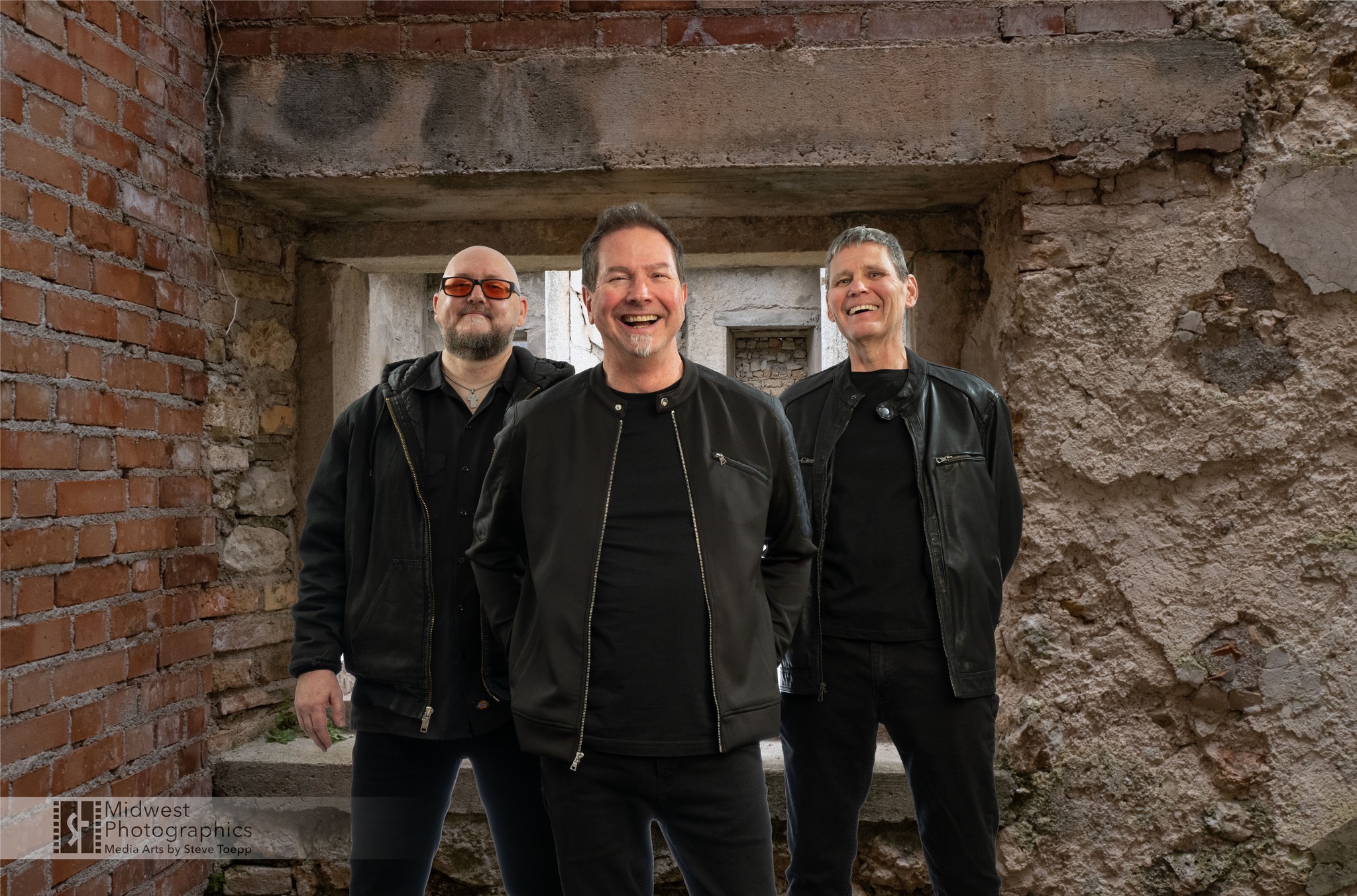 Q Sonics standing together in front of a brick and stone wall
